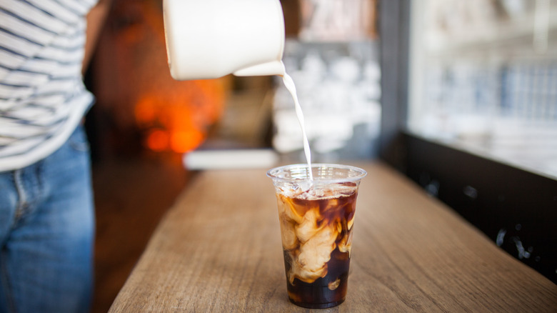 Cream being poured into a cold brew