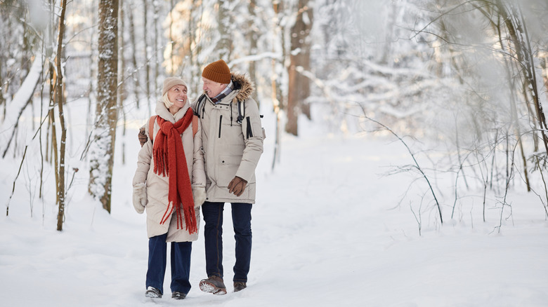 Two retirees enjoying a walk in a snowy forest