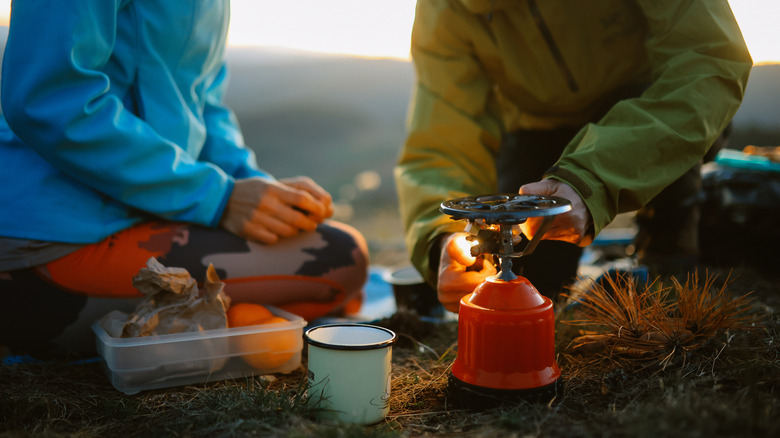 Two campers preparing dinner over a camping stove.